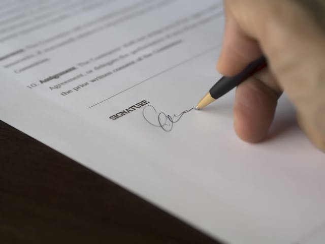 A close-up of a person signing a contract. 