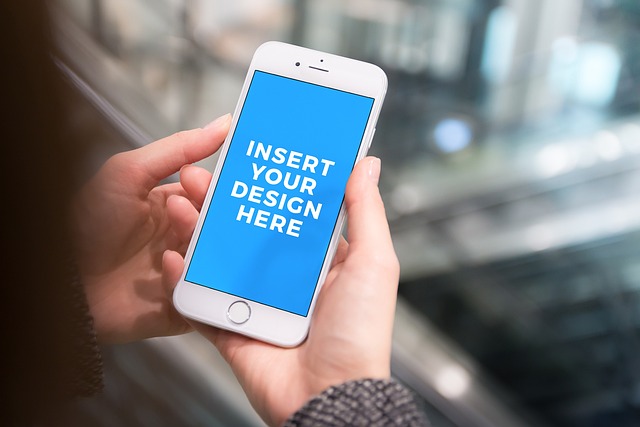 A close-up of a person holding a white smartphone with a blue screen that displays the phrase “Insert your design here.” 
