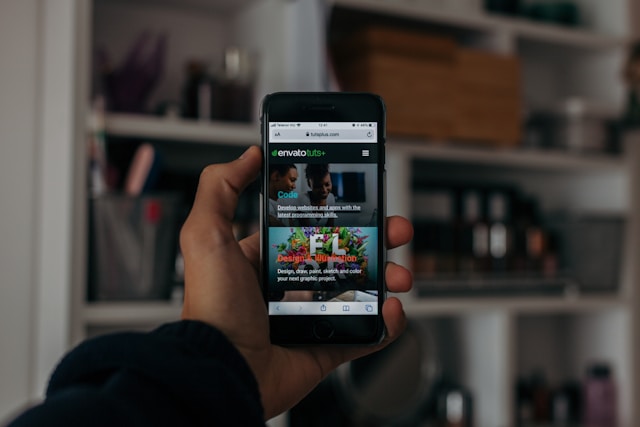 A person holding up a turned-on smartphone on the homepage of an app.