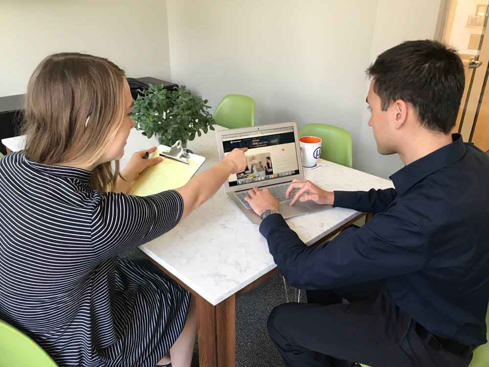 A Page Flows screenshot from Measuringu of two people sitting at a table with a laptop and a clipboard. 
