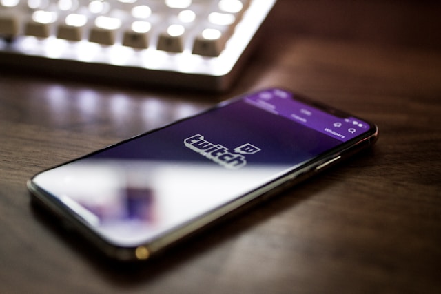 A close-up of a mobile phone which displays the Twitch mobile app on its screen. 
