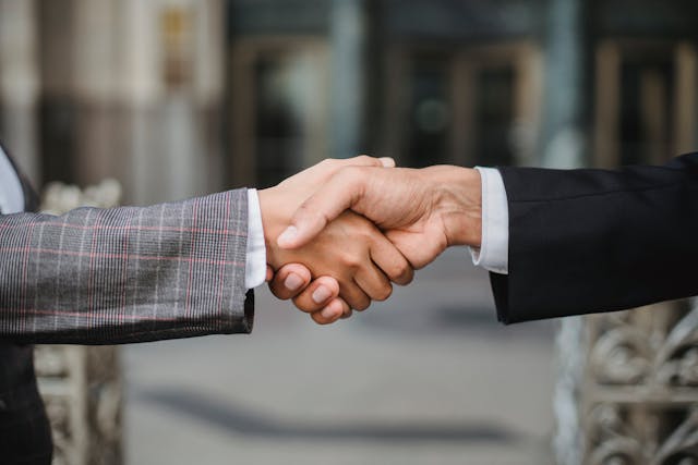 A close-up of two people in suits shaking hands. 
