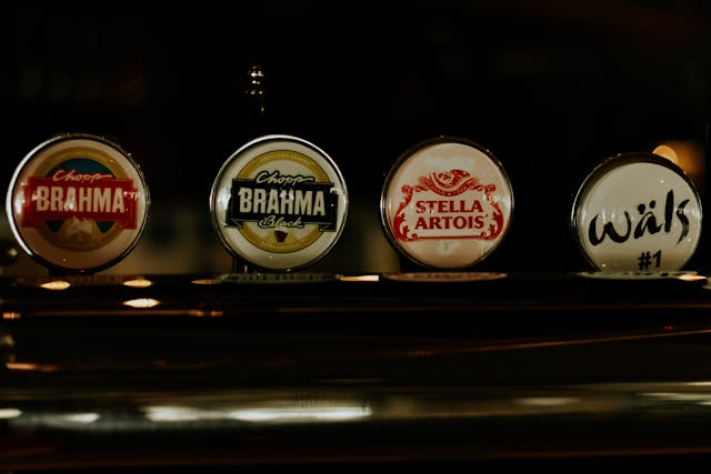 A close-up of different bottle caps that display the logo design of various beer companies. 
