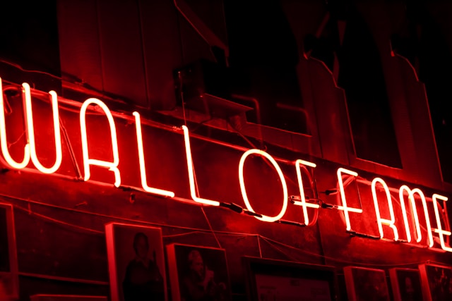 A close-up of a red neon sign that reads the phrase “Wall of Fame.” 
