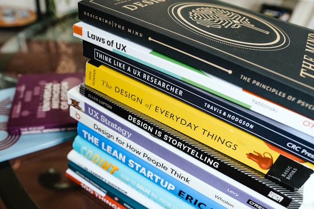 A close-up of a stack of books that relate to UX design and UX research.