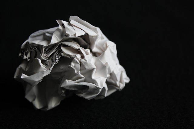 A close-up of a crumpled ball of paper against a black background. 
