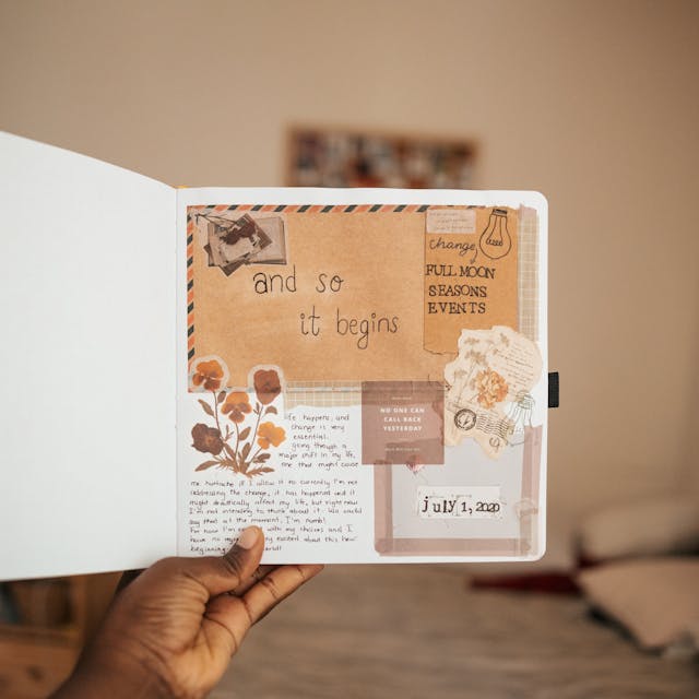 A person holding a scrapbook that contains handwriting, images, and illustrations.