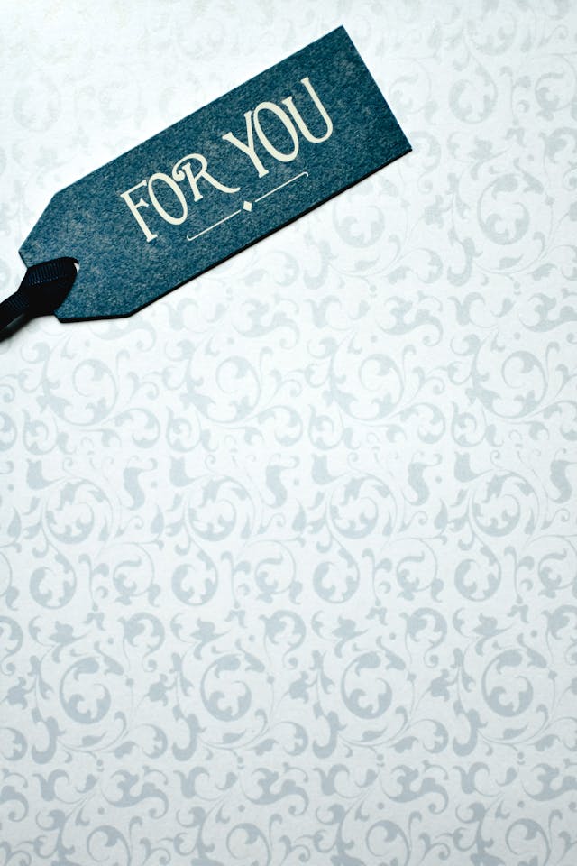 A dark blue gift tag reads the phrase, “For You” against a light blue and white patterned background.