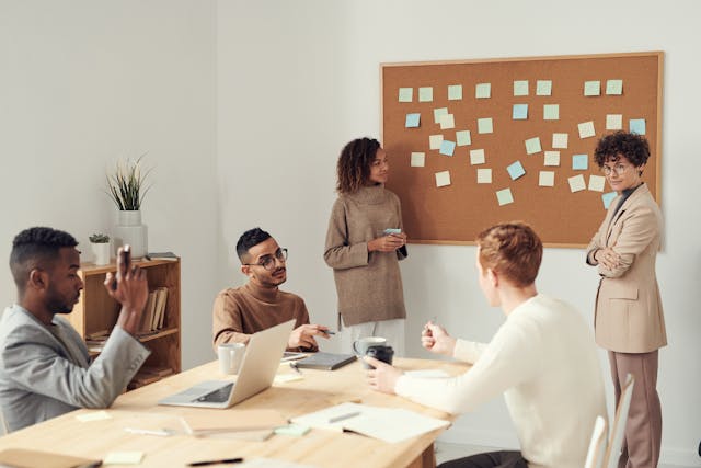 A group of co-workers deliberate with one another during a meeting. 