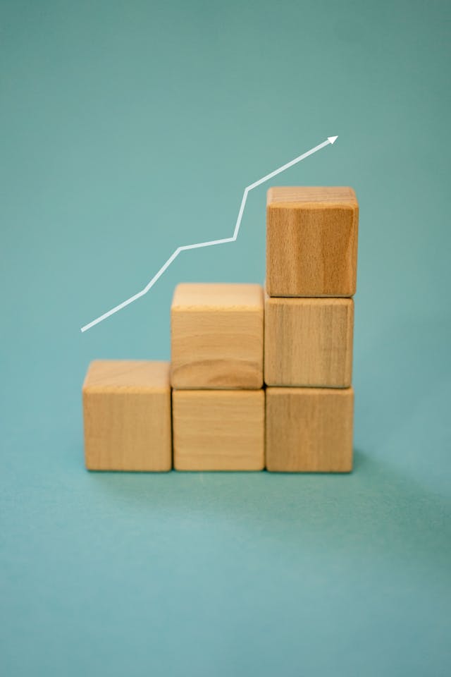 A white arrow steadily ascends over the top of a series of wooden blocks. 
