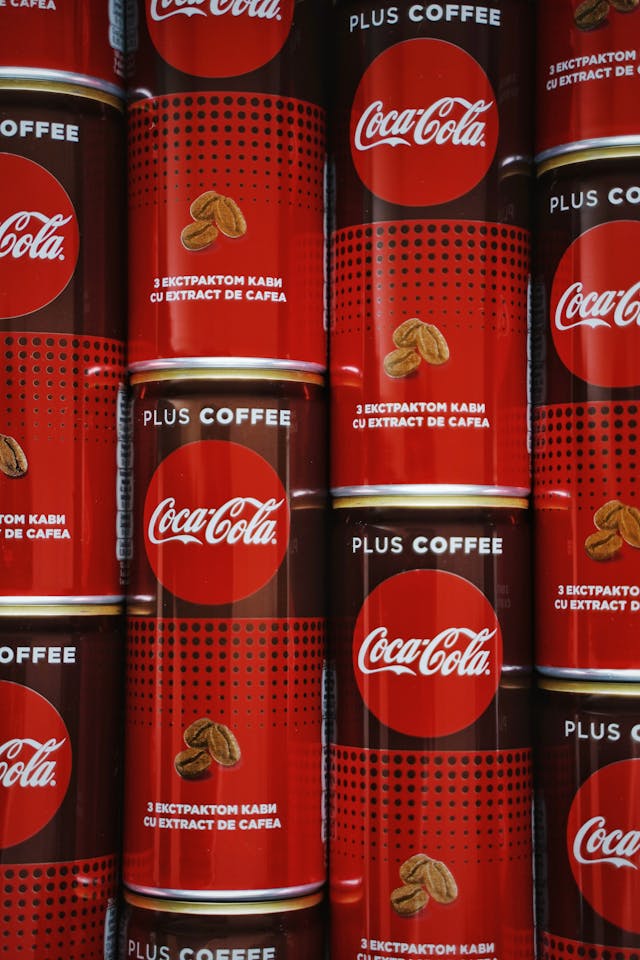 A close-up of multiple towers of identical Coca-Cola cans, representing a brand’s visual consistency. 
