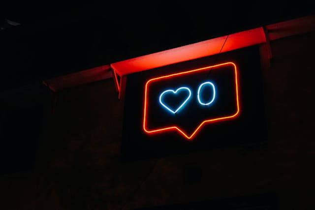 A bright red and blue neon sign that depicts a heart and the number 0, resembling the “like” system on social media.