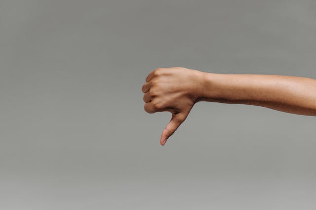 A photo of a person’s arm making a thumbs-down gesture, representing unhappy clients.