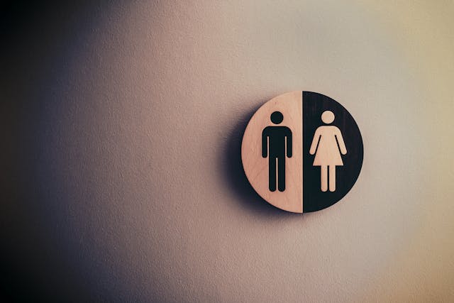 A black and white sign on a wall that depicts the simple silhouettes of a man and a woman.