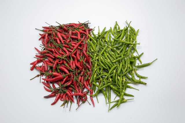 A pile of red and green peppers placed next to each other, representing complementary color schemes.