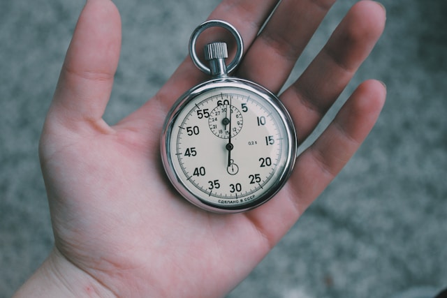 A close-up of a person holding a white and silver pocket watch. 
