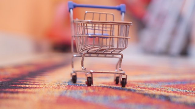 Small model shopping cart on a red rug.
