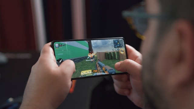 A close-up of a person playing a first-person shooter on their mobile phone.