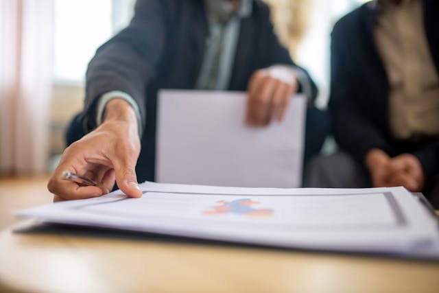 A close-up of a businessman picking up a page from a portfolio. 