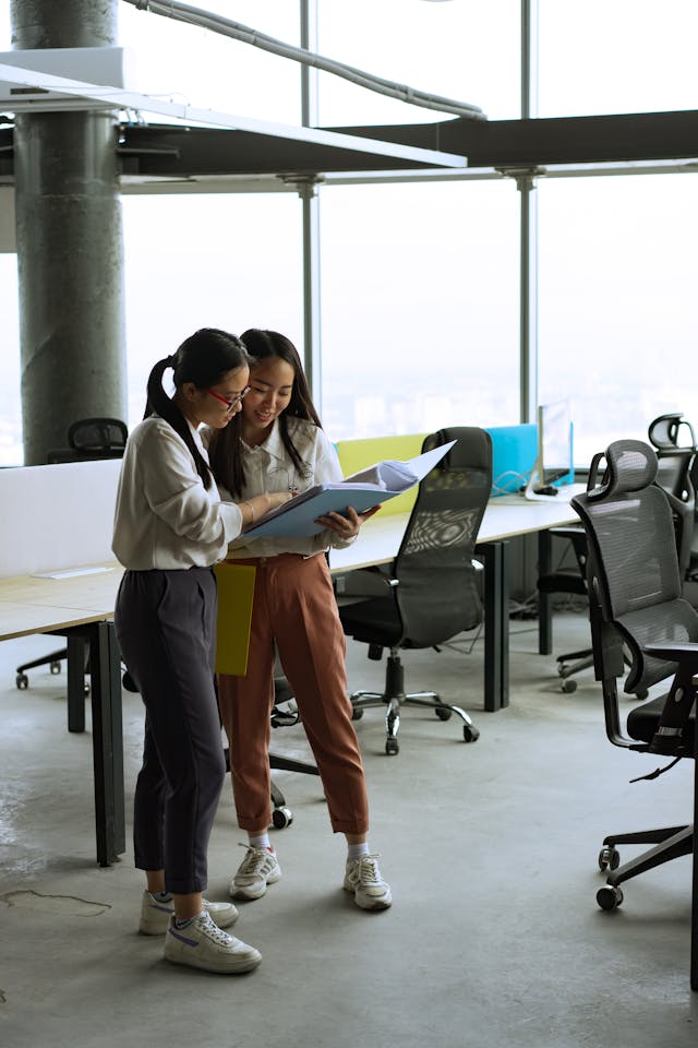 Two women looking at a blue folder in the office.
