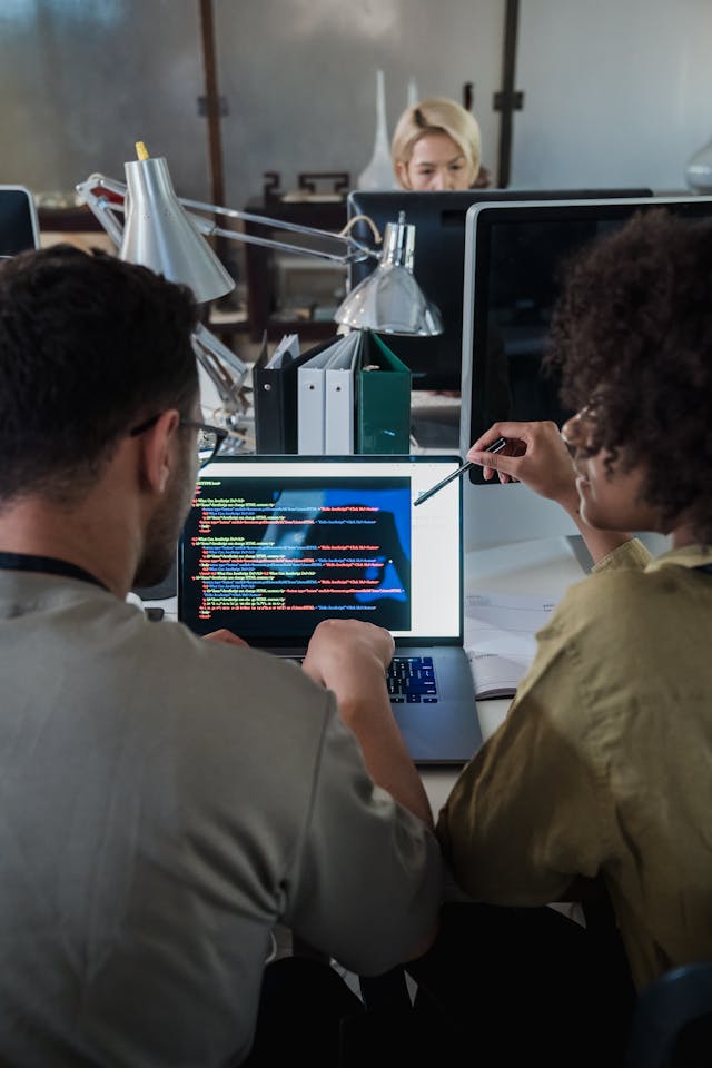 Two people discussing data displayed on a laptop screen.
