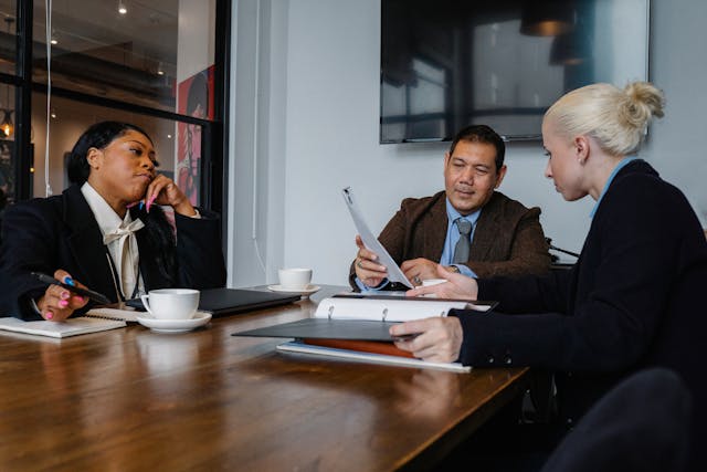 Three people sitting around a table.
