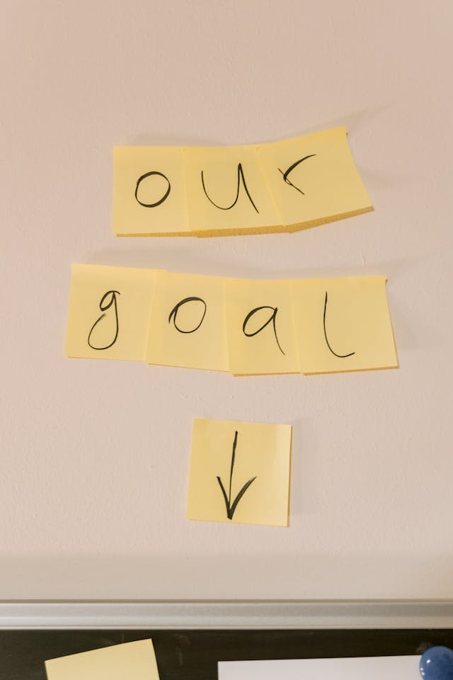 A group of yellow sticky notes appear together to read the phrase “Our goal.”
