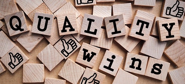 A close-up of a group of wooden Scrabble tiles that spell out the phrase, “Quality wins.”