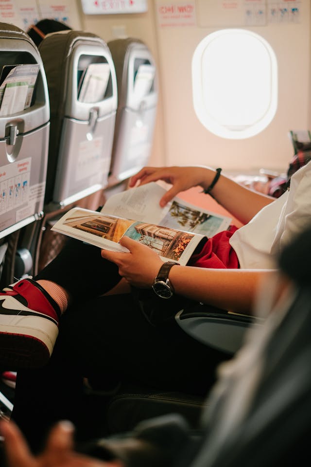 A person reading a magazine while sitting on a plane.