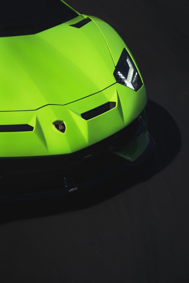 The hood of a lime-green Lamborghini car against a black background.  
